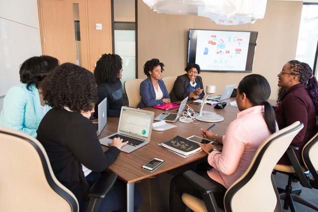 seven black women sitting at conference room table