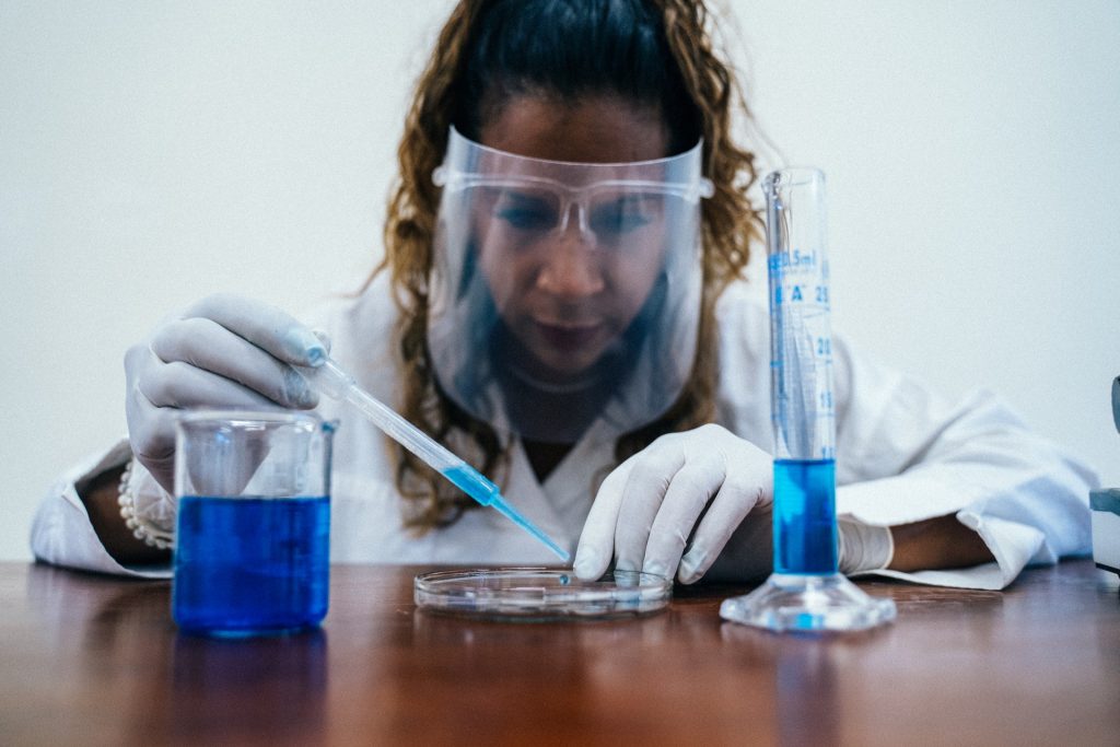female scientist using a pipette and dropping blue liquid into a petri dish