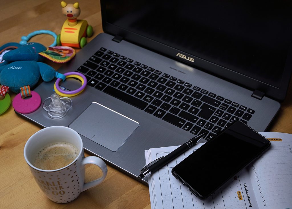 laptop on table with coffee mug and children's toys